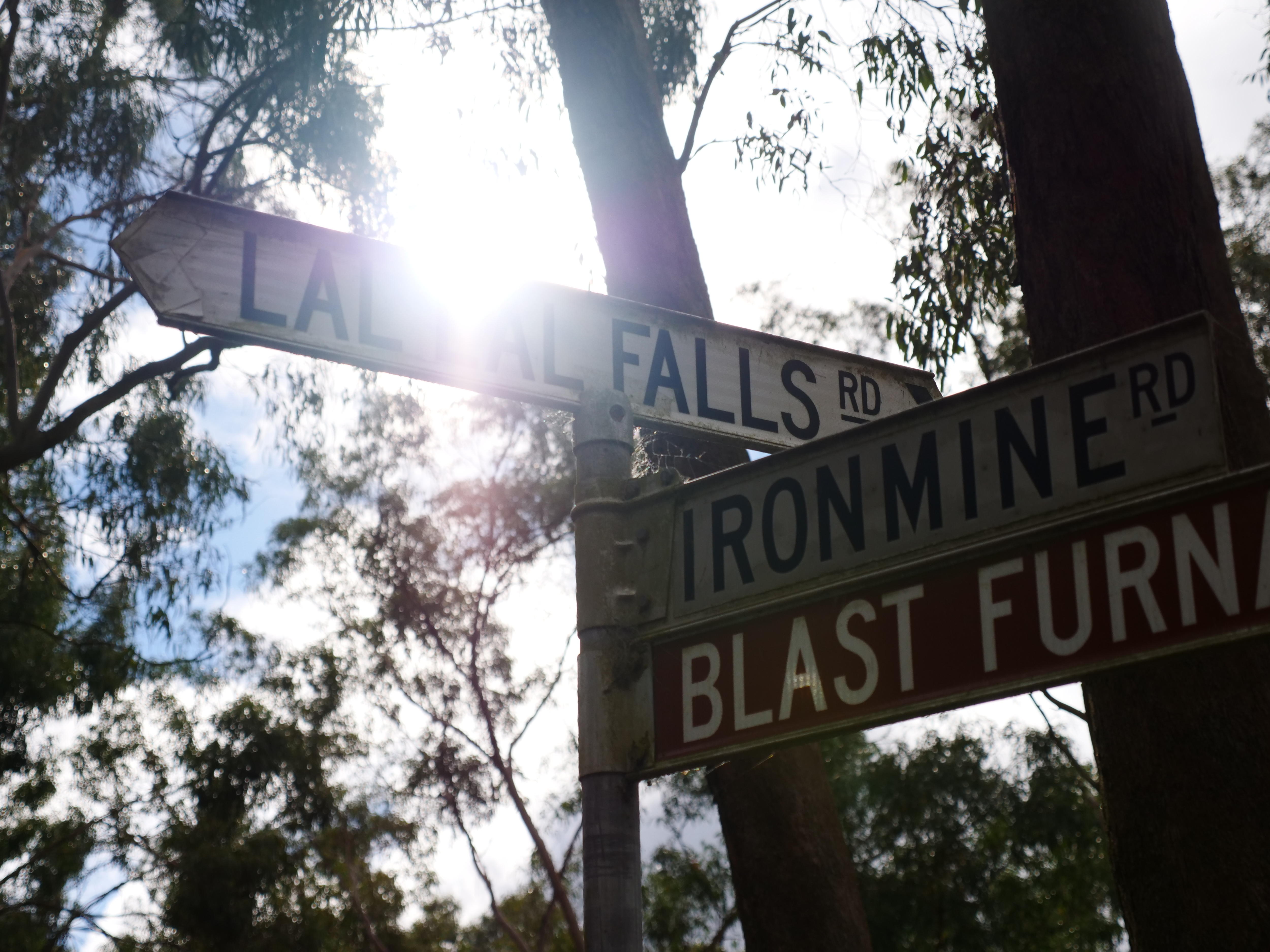 A sign  that says Lal Lal falls with the sun shining through