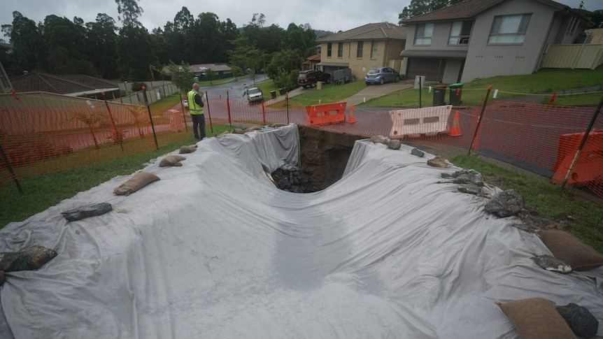 A tarped over hole in a suburban street on an overcast day