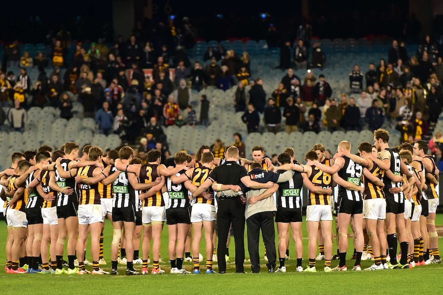 Hawthorn and Collingwood players embrace after the final siren to honour Phil Walsh