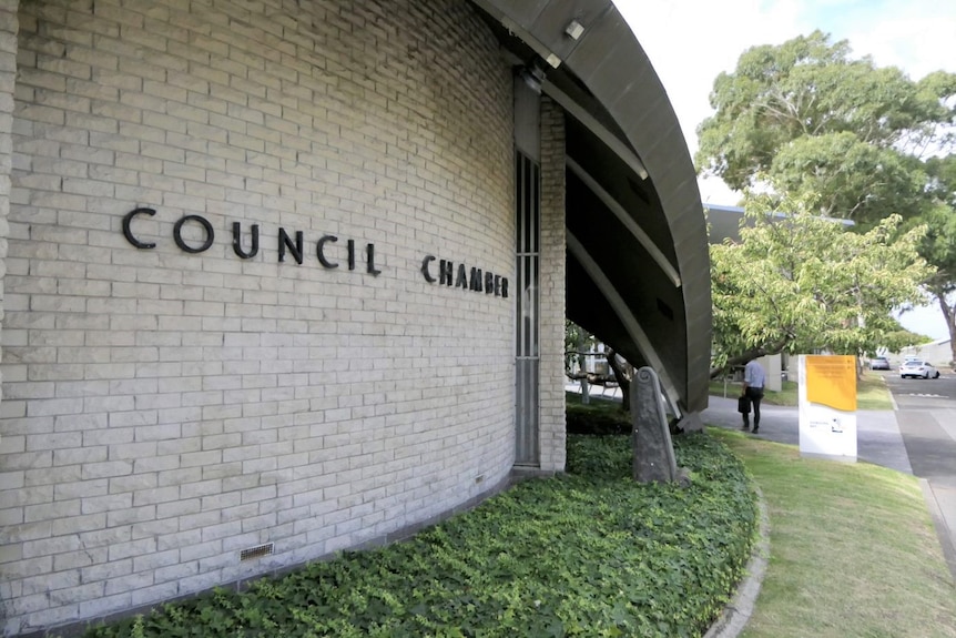 A tight picture of a cylindrical brick wall at the front of the council building