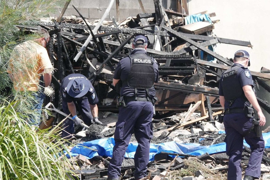 Police officers use shovels to sift through the rubble.