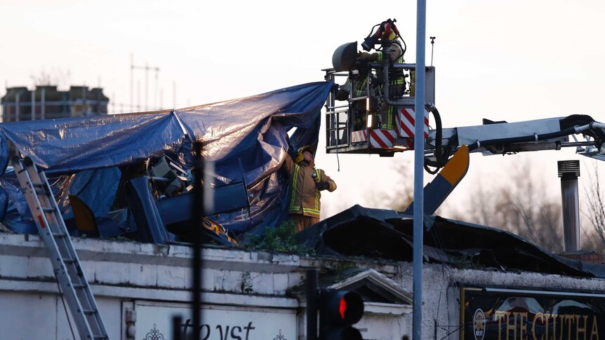Rescue workers cover the wreckage of a police helicopter which crashed onto the roof of the Clutha Vaults pub in Glasgow.