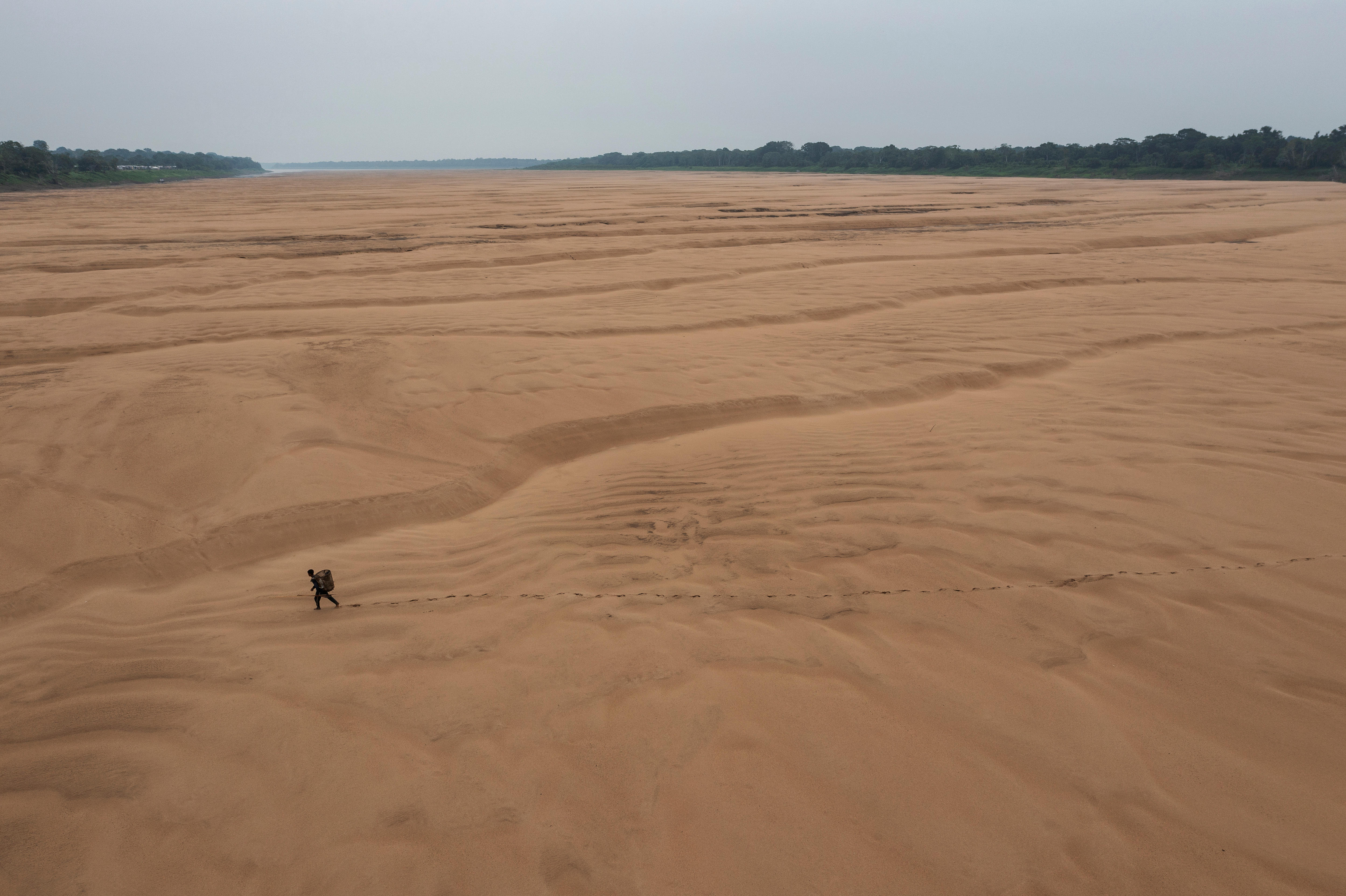 An overhead shot of a person walking across a sandy plane