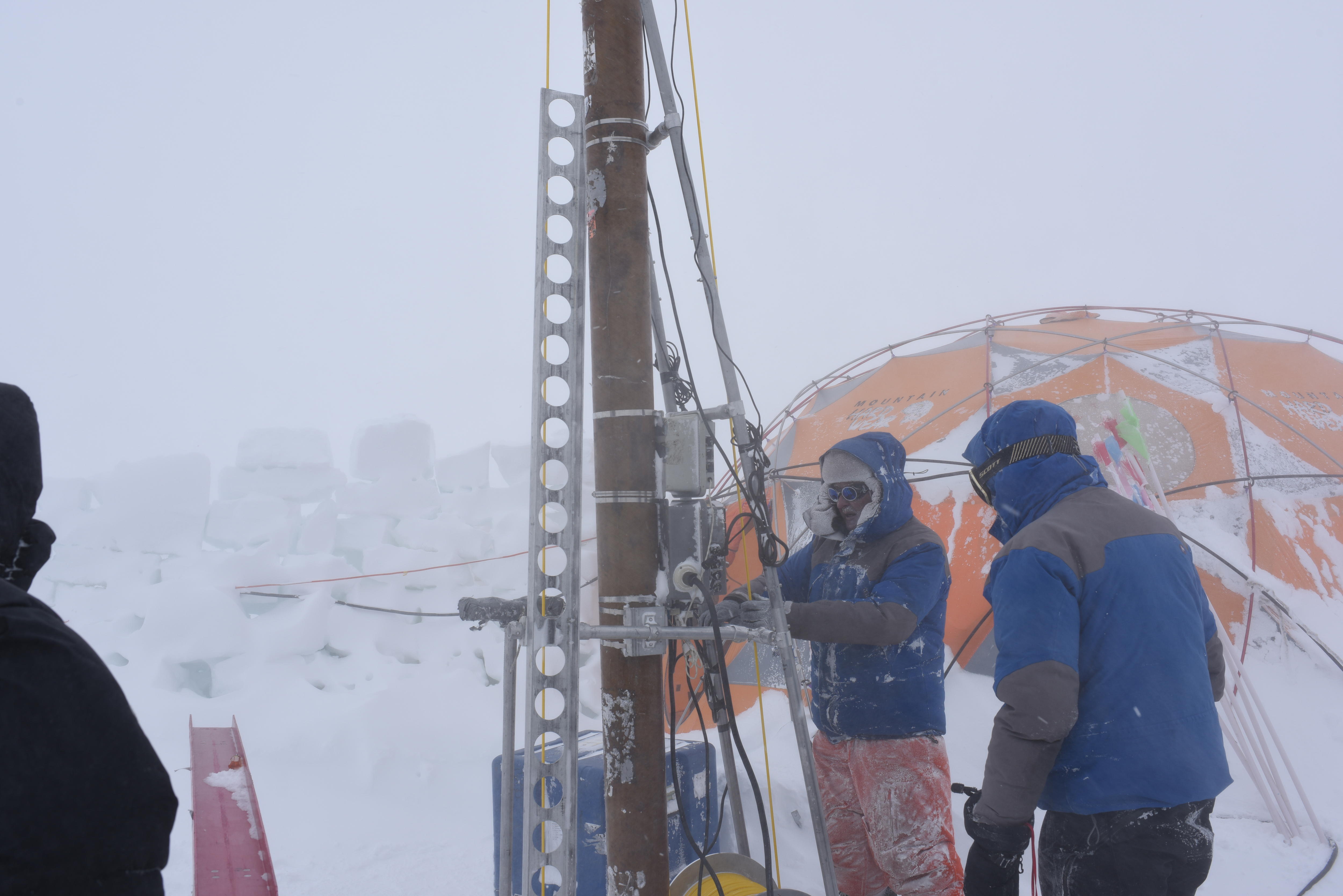 People wearing winter gear looking at equipment