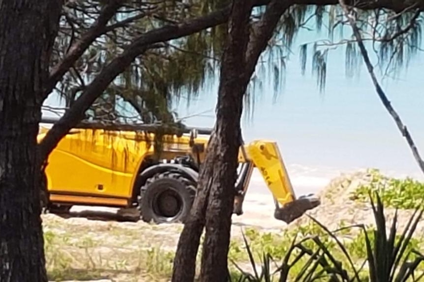 An excavator on a beach.
