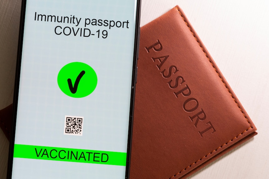 一个显示有“新冠疫苗接种护照”的智能手机被放在护照旁。