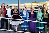 Seven women on a ramp, some of them in bright Afghan traditional dress