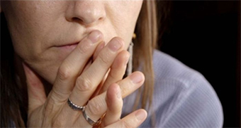 Woman holding hands together near her mouth.