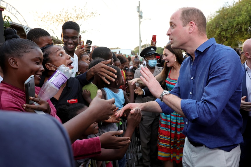 Prince William and Catherine shake hands with people during a visit to Trench Town in the Caribbean.