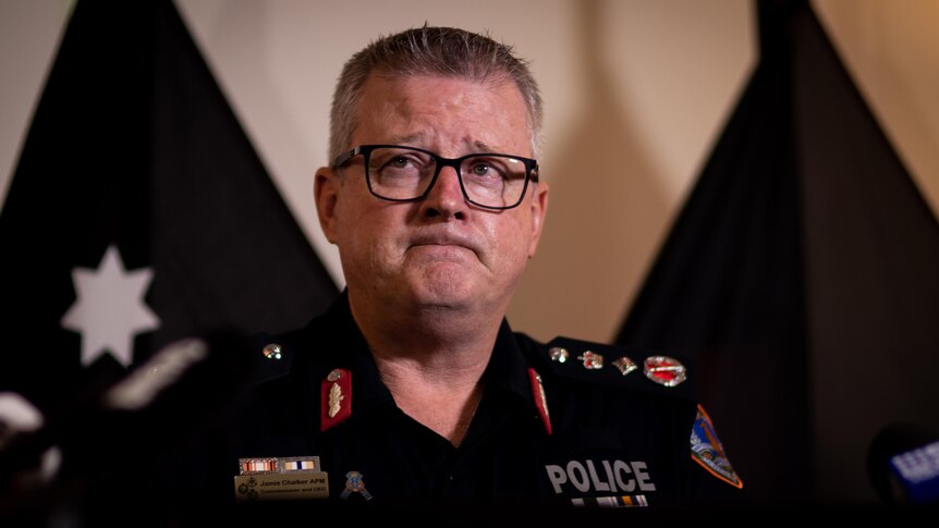 A man in a NT Police uniform standing at a lectern inside a room, looking exasperated.