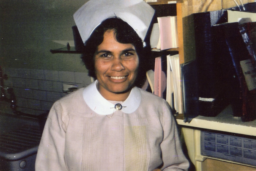 A medium shot of an Indigenous Australian woman smiling and working as a nurse in a hospital