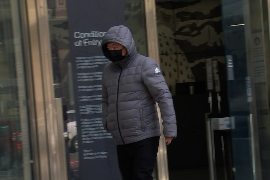 Cheng Li wears a black face mask and dark puffer jacket with the hood on as he left court.