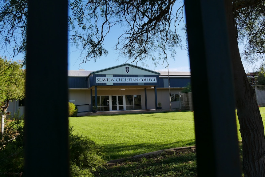 Two bars blurred in the foreground and a green grass lawn and blue and white school building in the background. 