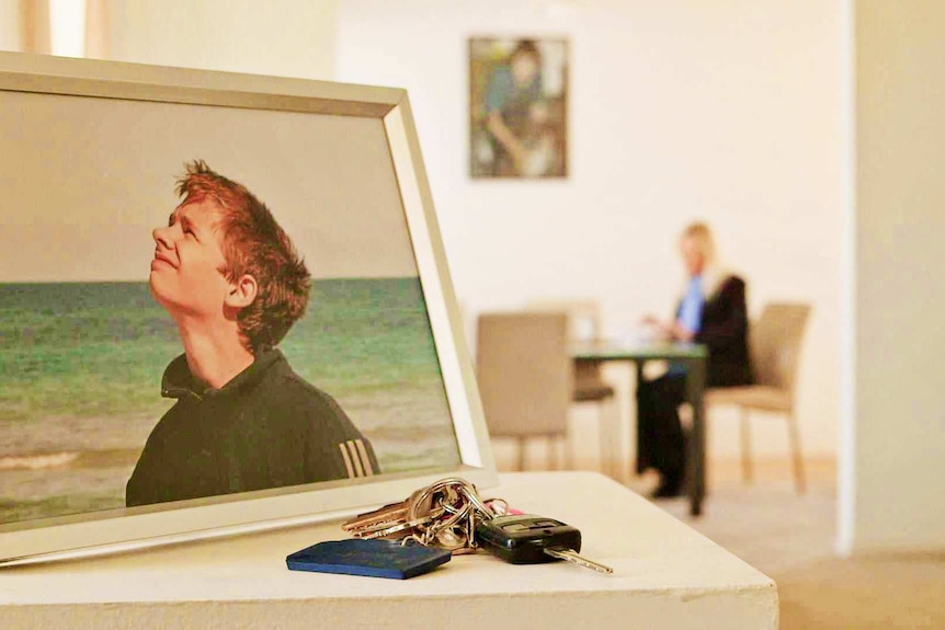 A framed photo of a Logan West with his mother in sitting at a table in the background