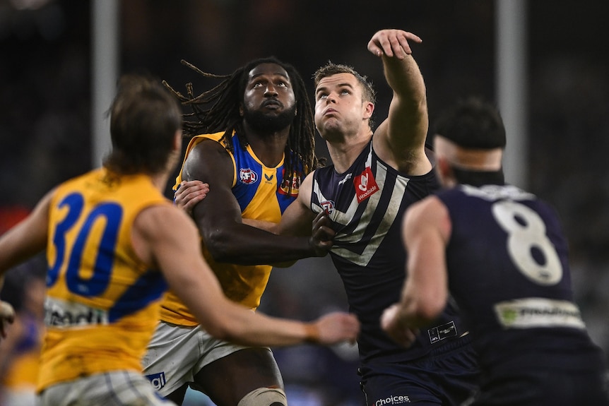 Nic Naitanui and Sean Darcy look up and grapple with two other players framing them in the foreground