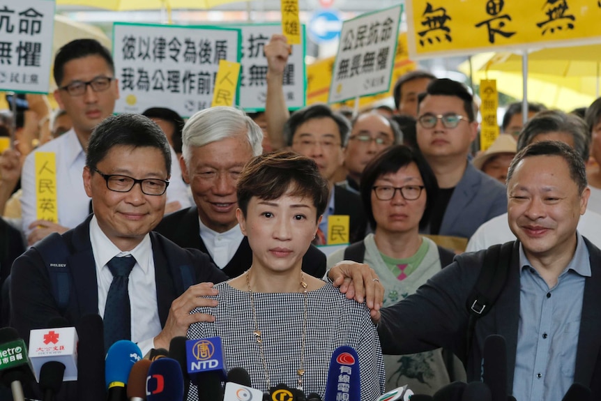 Tanya Chan in front of the microphones with Benny Tai, Chan Kin-man and Chu Yiu-ming surrounded by supporters with placards.