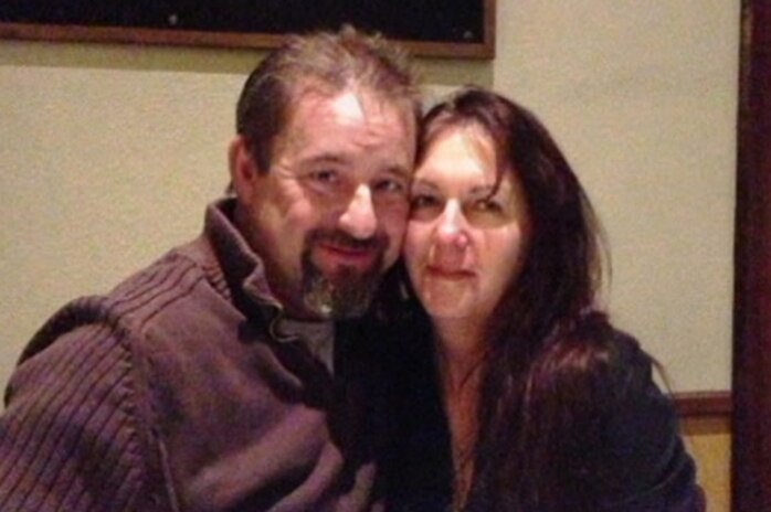 A man and a woman hug at a restaurant table.