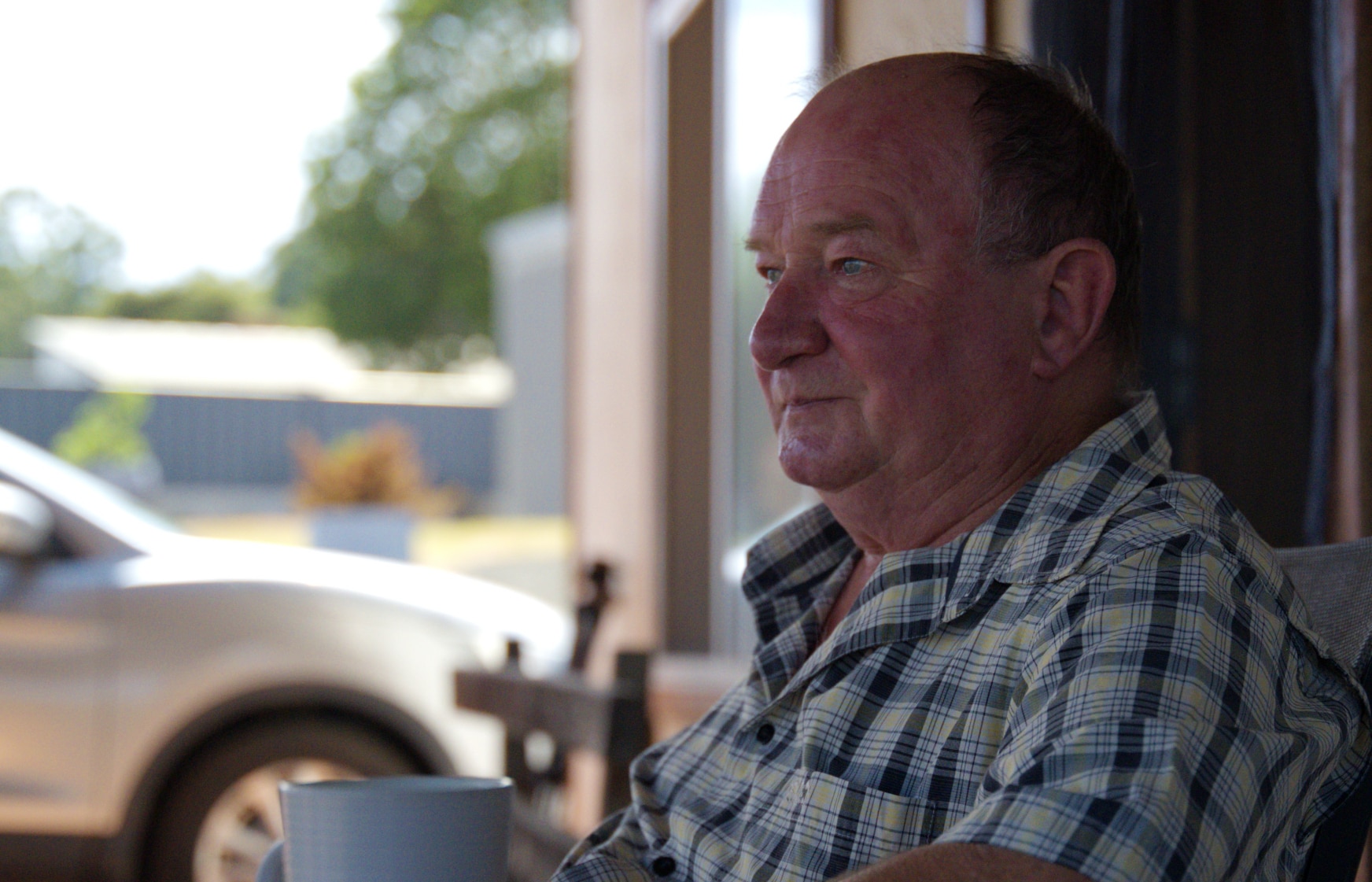 Um homem de camisa xadrez olha para o lado.