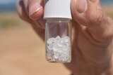 Person holds tiny jar filled with microplastics