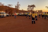 Workers gathered for a socially distanced outdoor mine meeting at sunrise.
