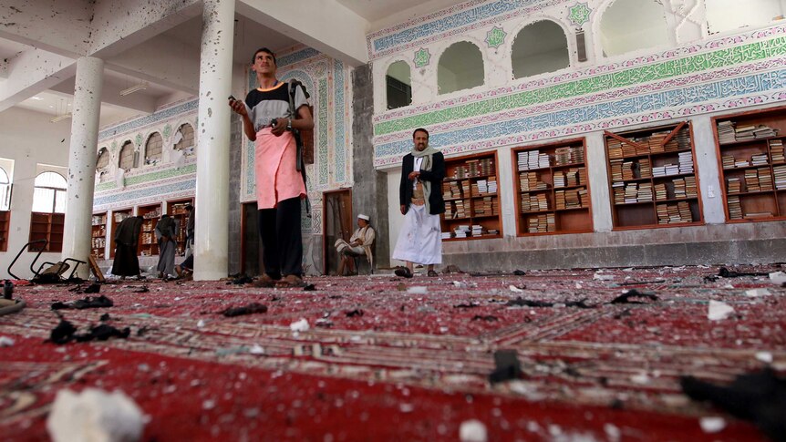 Men inspect the damage following a bomb explosion at the Badr mosque in southern Sanaa.