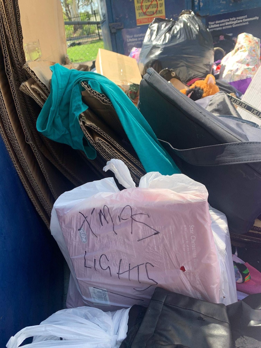 Donations and items strewn in front of charity bins.