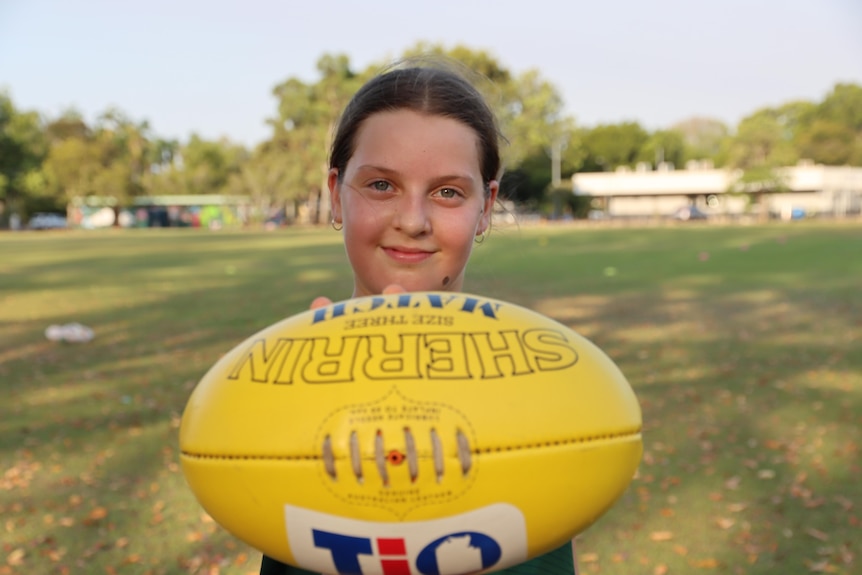  Isabell Dewsbury holds a football up at Nightcliff Oval.