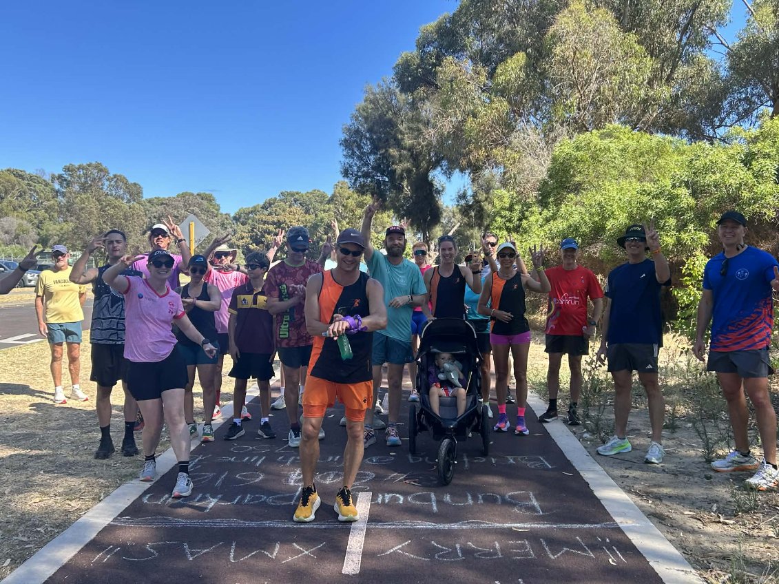 Una toma amplia de unas 20 personas paradas en una pista de atletismo.