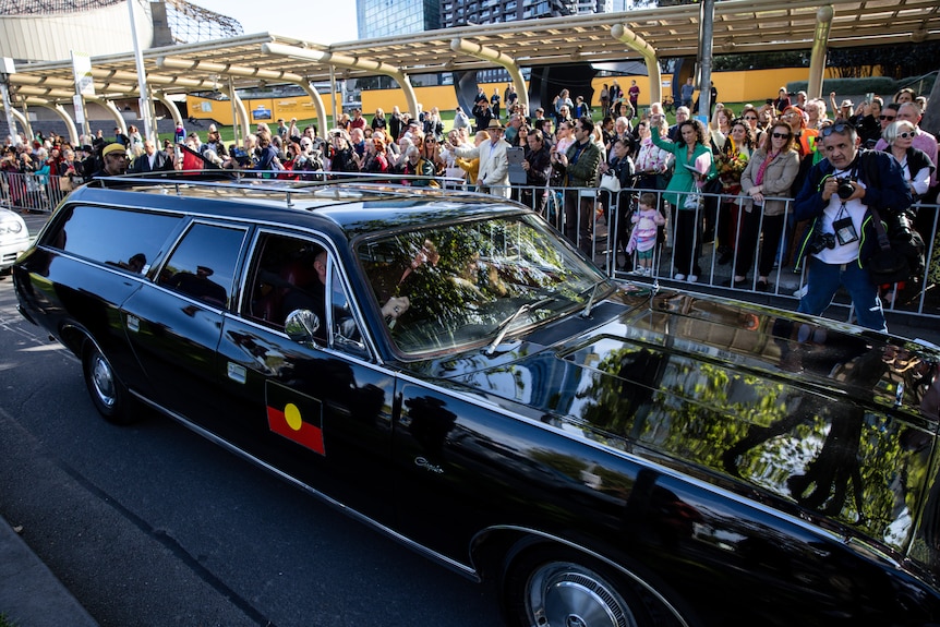 A black hearse with an Aboriginal flag on the side.