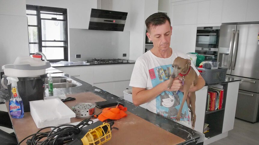 Idalia resident Wayne McDonald stands in his house kitchen which is still being renovated, he holds his dog