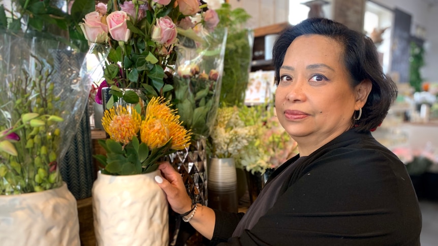 a woman is standing next to pots of colourful flowers