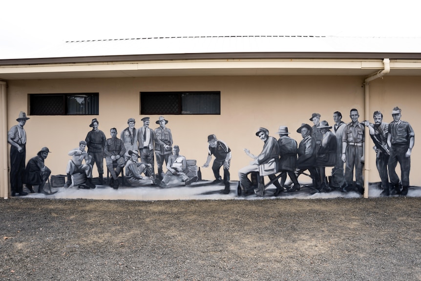A mural painted on a wall showing 20 men involved in a two up game