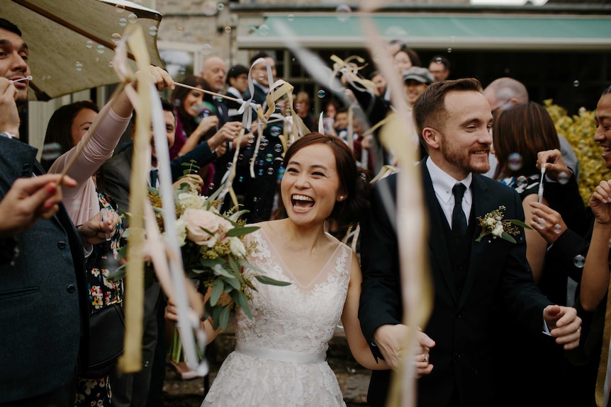 A just-married couple walk past friends and family after the wedding ceremony.