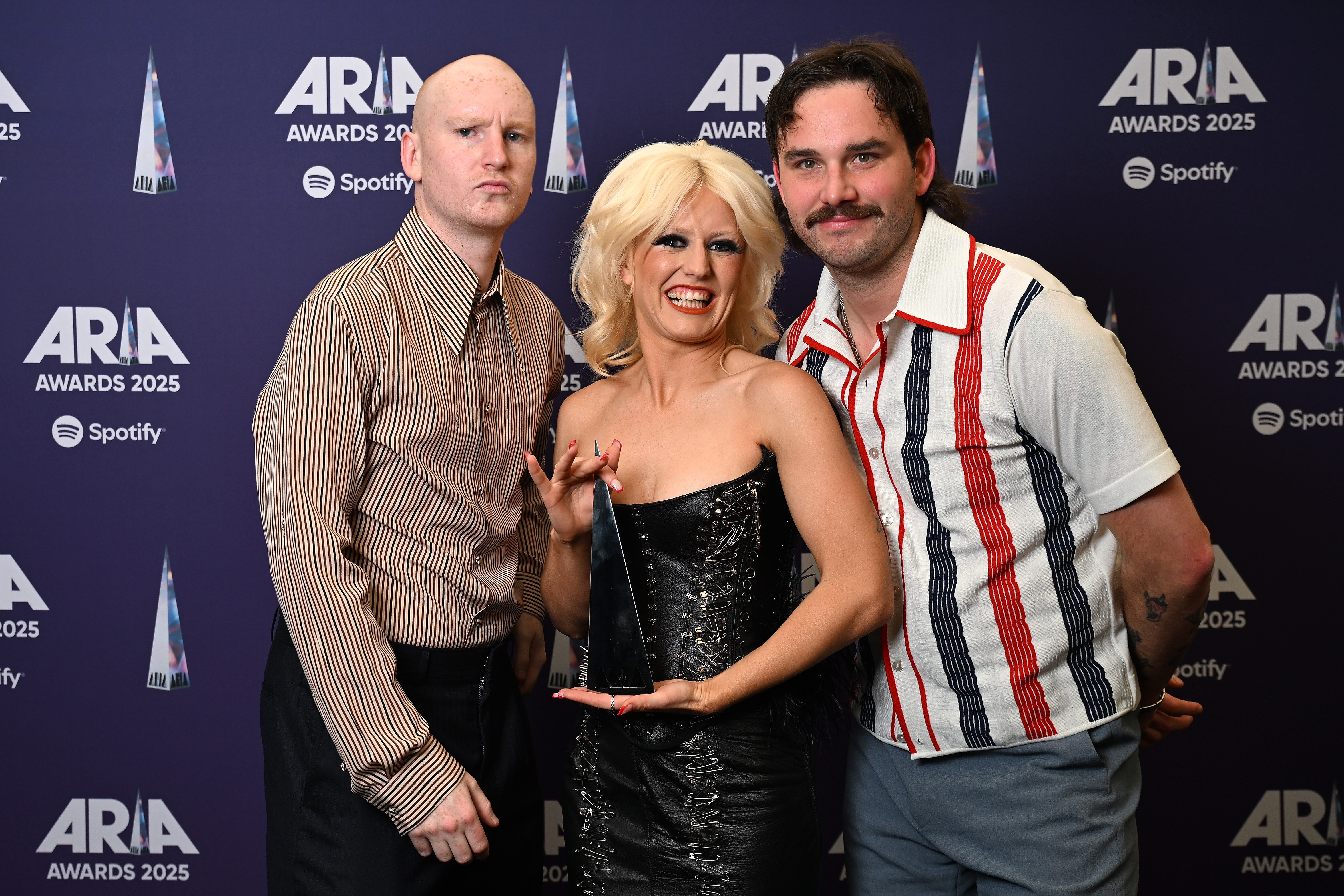Gus, Amy Taylor and Bryce of Amyl and The Sniffers pose together with an ARIA award