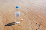 A bottle of Akuna Springs water on the beach.