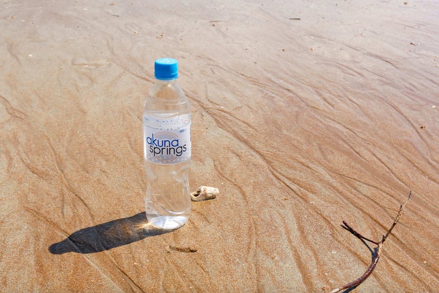 A bottle of Akuna Springs water on the beach.