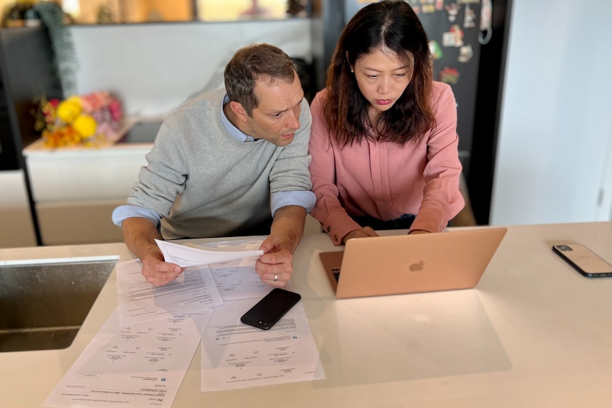 A man and a woman look at a laptop screen.