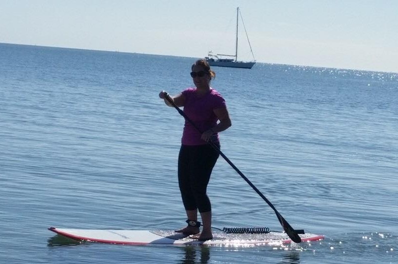 Jo Hickman stands on a paddle board at Raby Bay