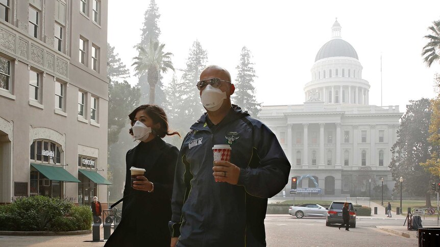 Two people wearing masks as they walk in the street in Sacramento California.