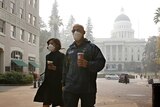 Two people wearing masks as they walk in the street in Sacramento California.