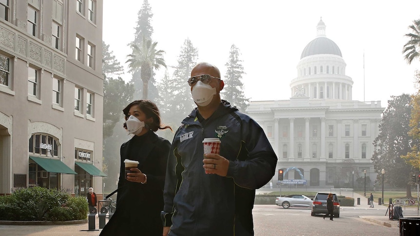 Two people wearing masks as they walk in the street in Sacramento California.