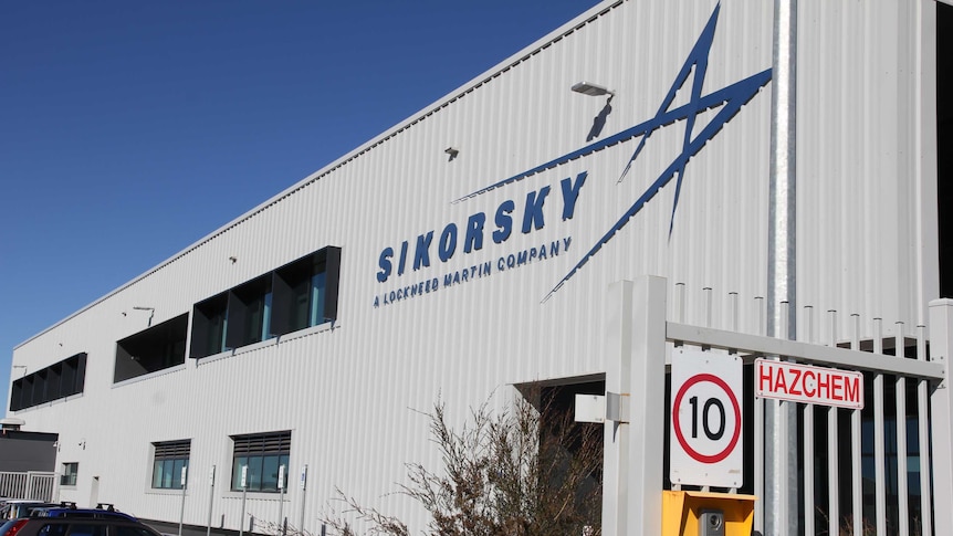 A large building behind a security gate. The building has the name Sikorski on the wall.