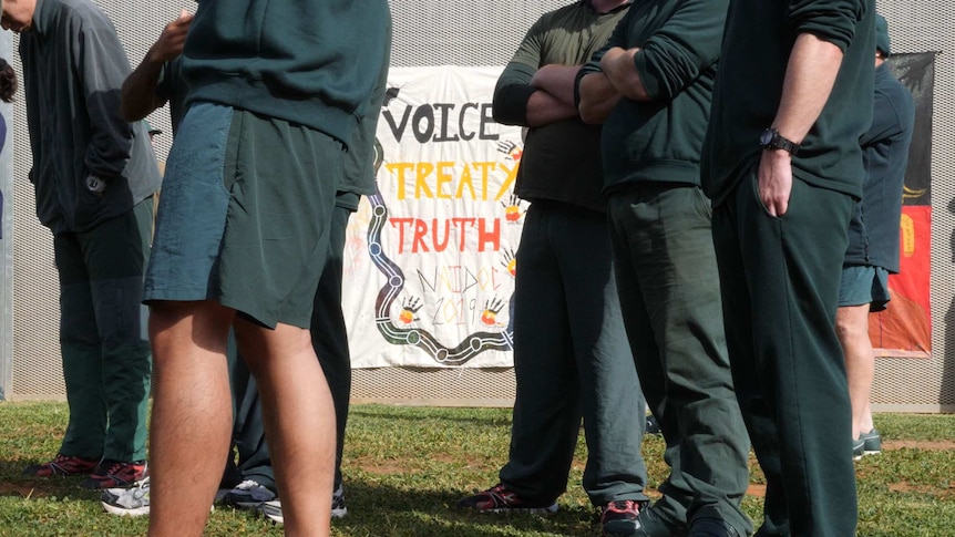 7 people in green clothing around a sign reading "voice treaty truth NAIDOC 2019"