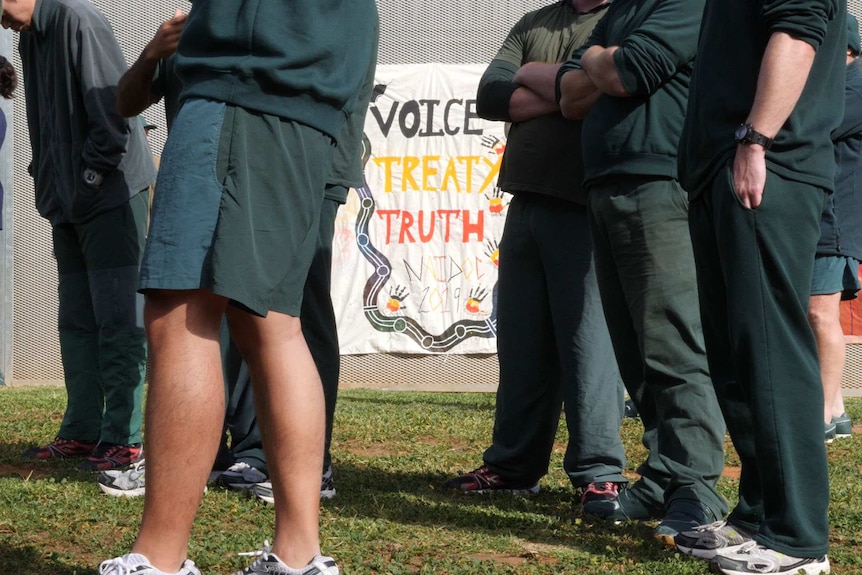 7 people in green clothing around a sign reading "voice treaty truth NAIDOC 2019"