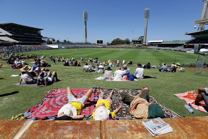 Spectators lie on the hill at the WACA