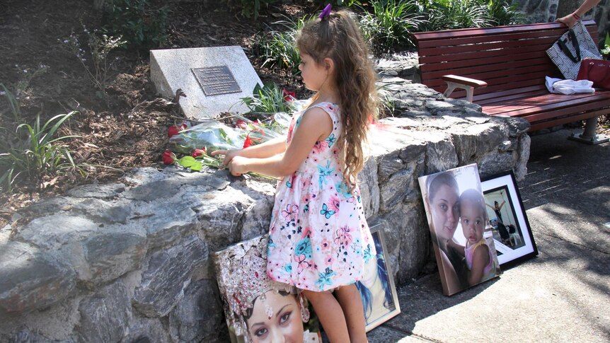 A four-year-old girl touches the roses laid in front of the domestic violence memorial.