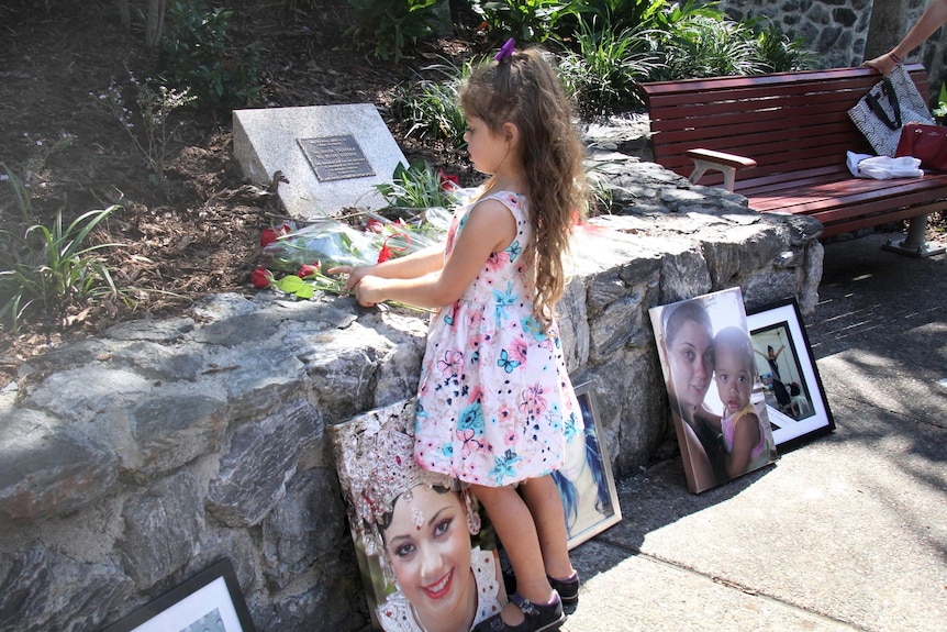 A four-year-old girl touches the roses laid in front of the domestic violence memorial.