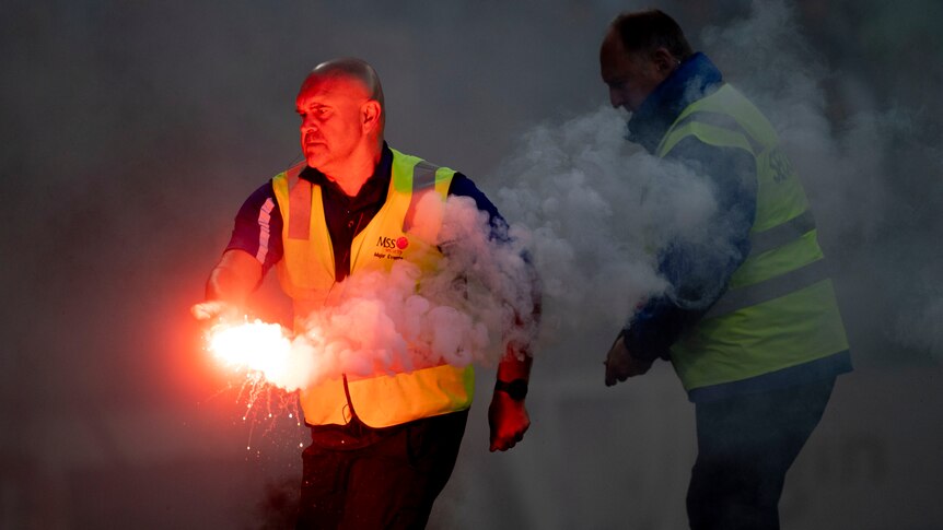 A security officer removes a flare at an A-League Men match in Melbourne.