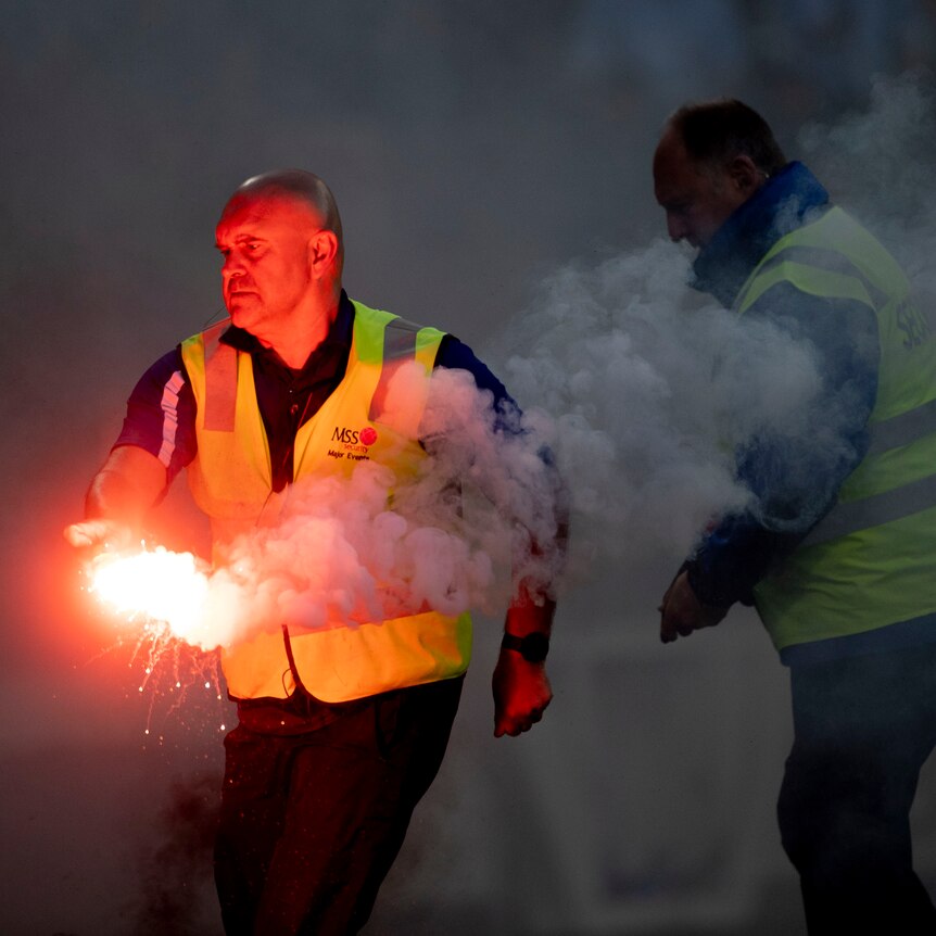 A security officer removes a flare at an A-League Men match in Melbourne.