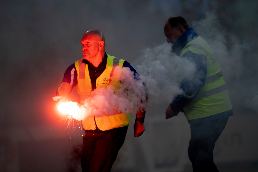 Un oficial de seguridad retira una bengala en un partido de la A-League Men en Melbourne.